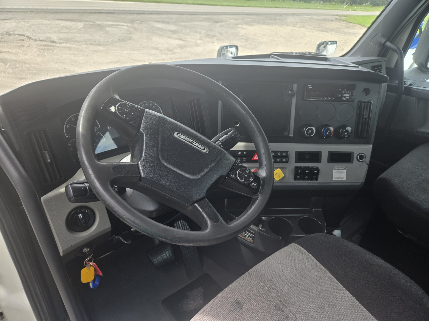 Cab interior of 2019 Freightliner Cascadia day cab showing steering wheel, dashboard, and center console.