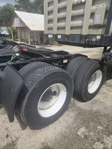 Truck rear dual wheels and fifth wheel area of a 2019 Freightliner Cascadia Day Cab tandem tractor showing dual rear axle tires and trailer hitch area.