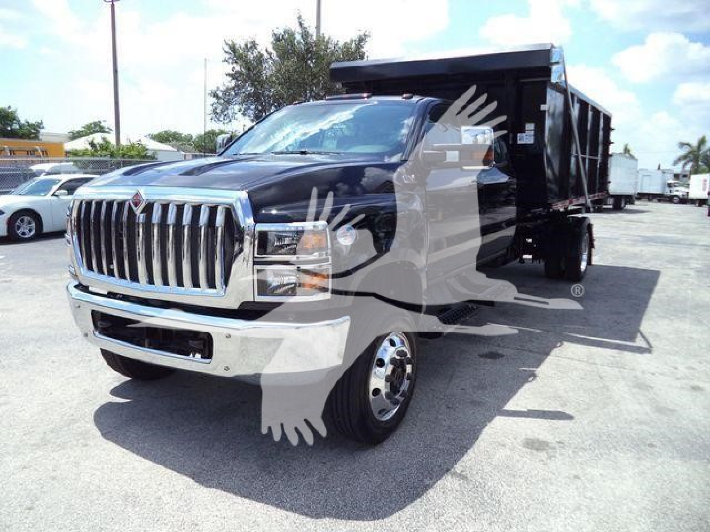 Blue dump truck front-left view showing chrome grille, dual headlights, large black dump bed, International logo on grille, side mirrors, and front bumper.