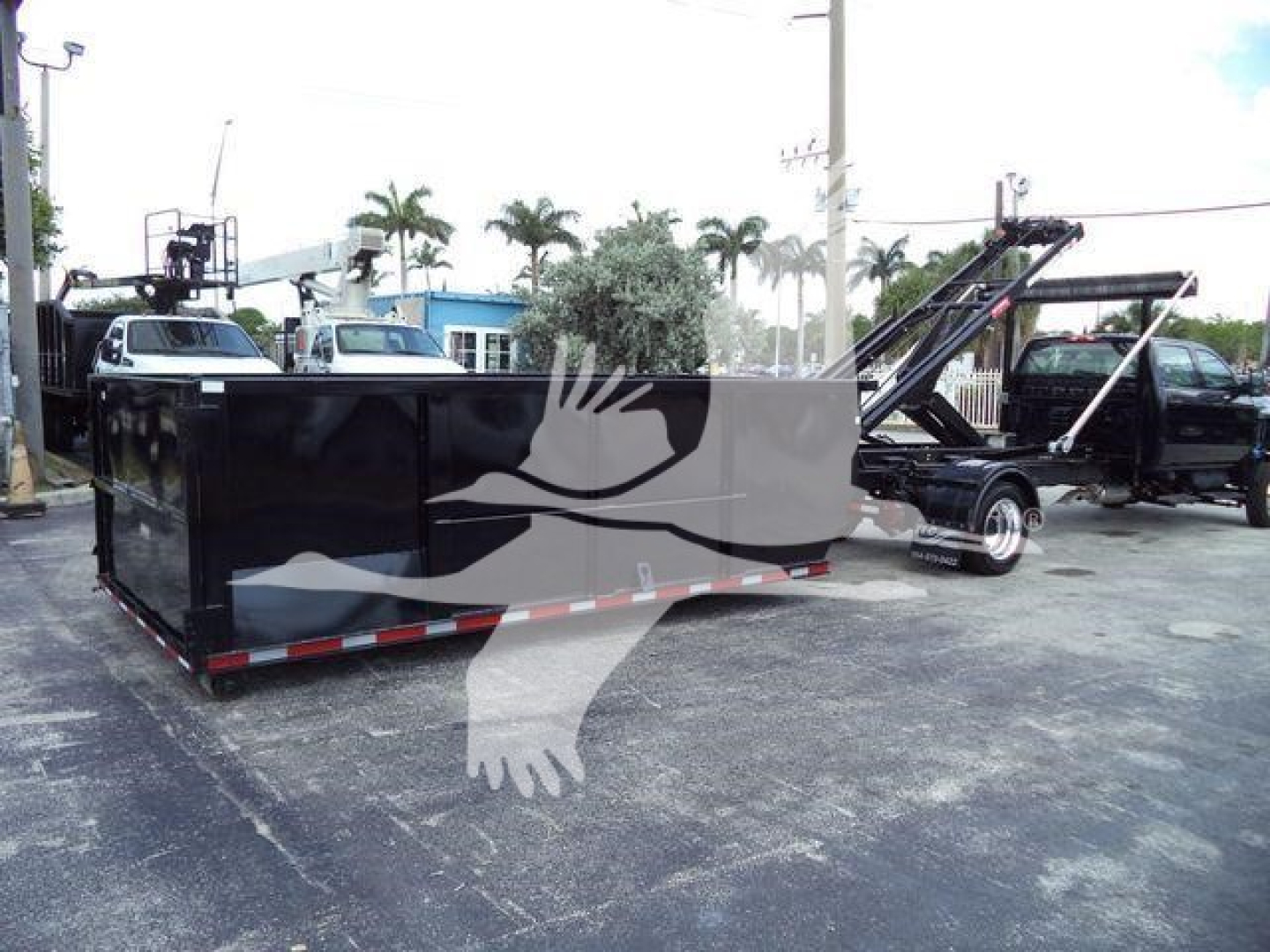 Image of a 2023 International CV rolloff truck with a long black dump box and a crane-like apparatus in a lot.