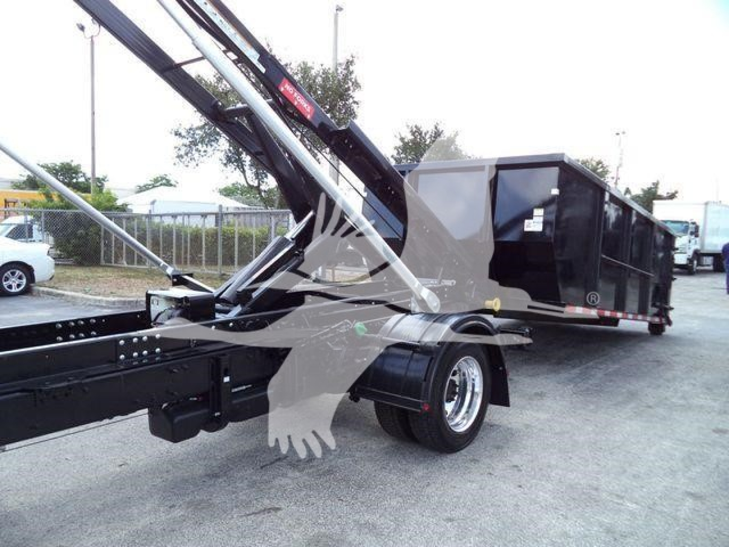 Truck mounted with crane arm showing rear cargo container and ballast in a lot.