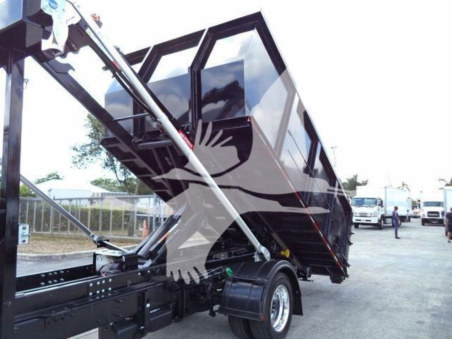 Truck truck bed dump hoist in raised position showing roll-off container chassis and hydraulic mechanism.