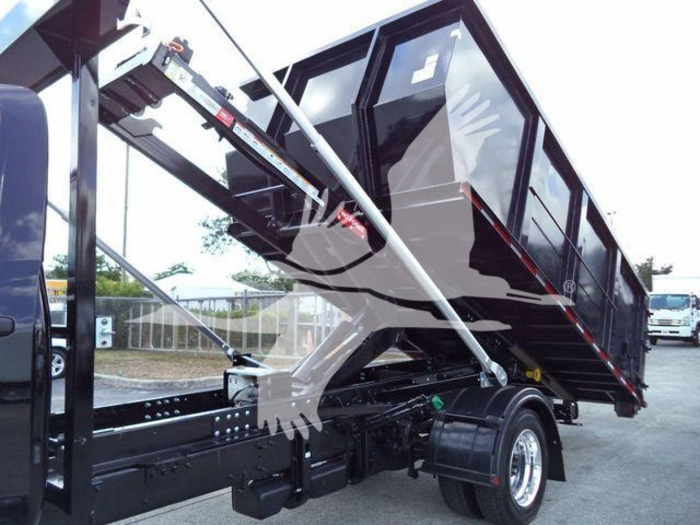 Truck bed with raised dumping trailer showing hydraulic arms and black/dark red container