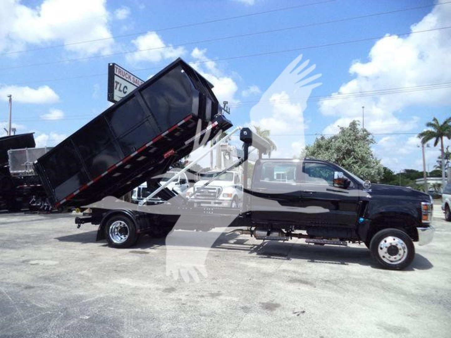 Truck with raised dump bed on a black International CV chassis, side view showing hydraulic lifting mechanism and dual rear wheels.