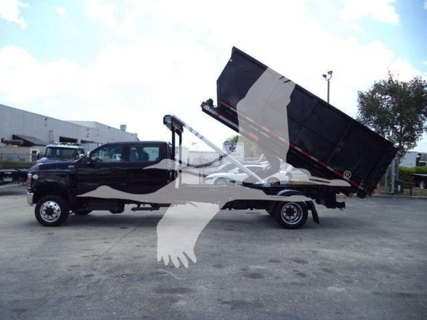 Dump truck with a raised dump bed, side view showing crane/hoist and towing chassis, International CV model in serviceable condition.
