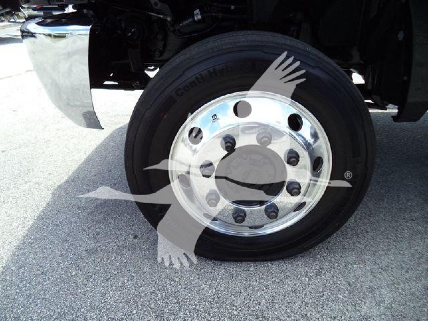 Truck front wheel with polished metal rim and black tire in chassis area showing hub and lug nuts.