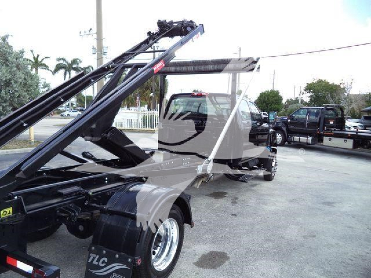 International CV roll-off truck with hydraulic arms and cab visible, side view