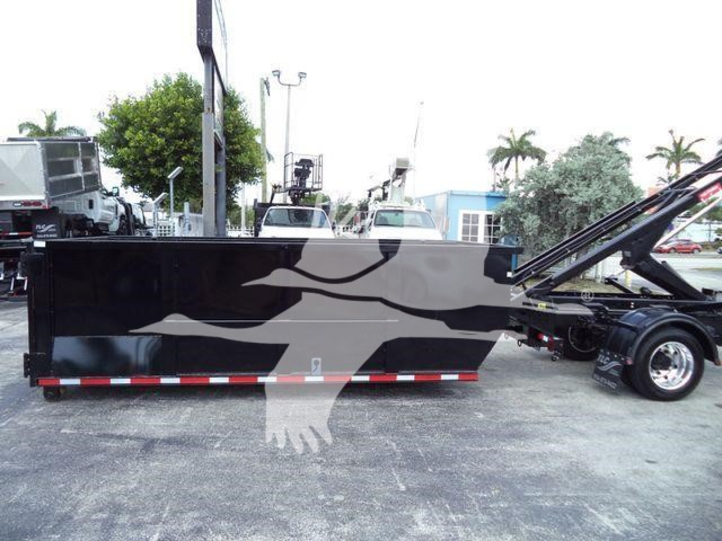 Tractor-trailer cargo bed with black and gray graphic on side, International CV roll-off truck in background