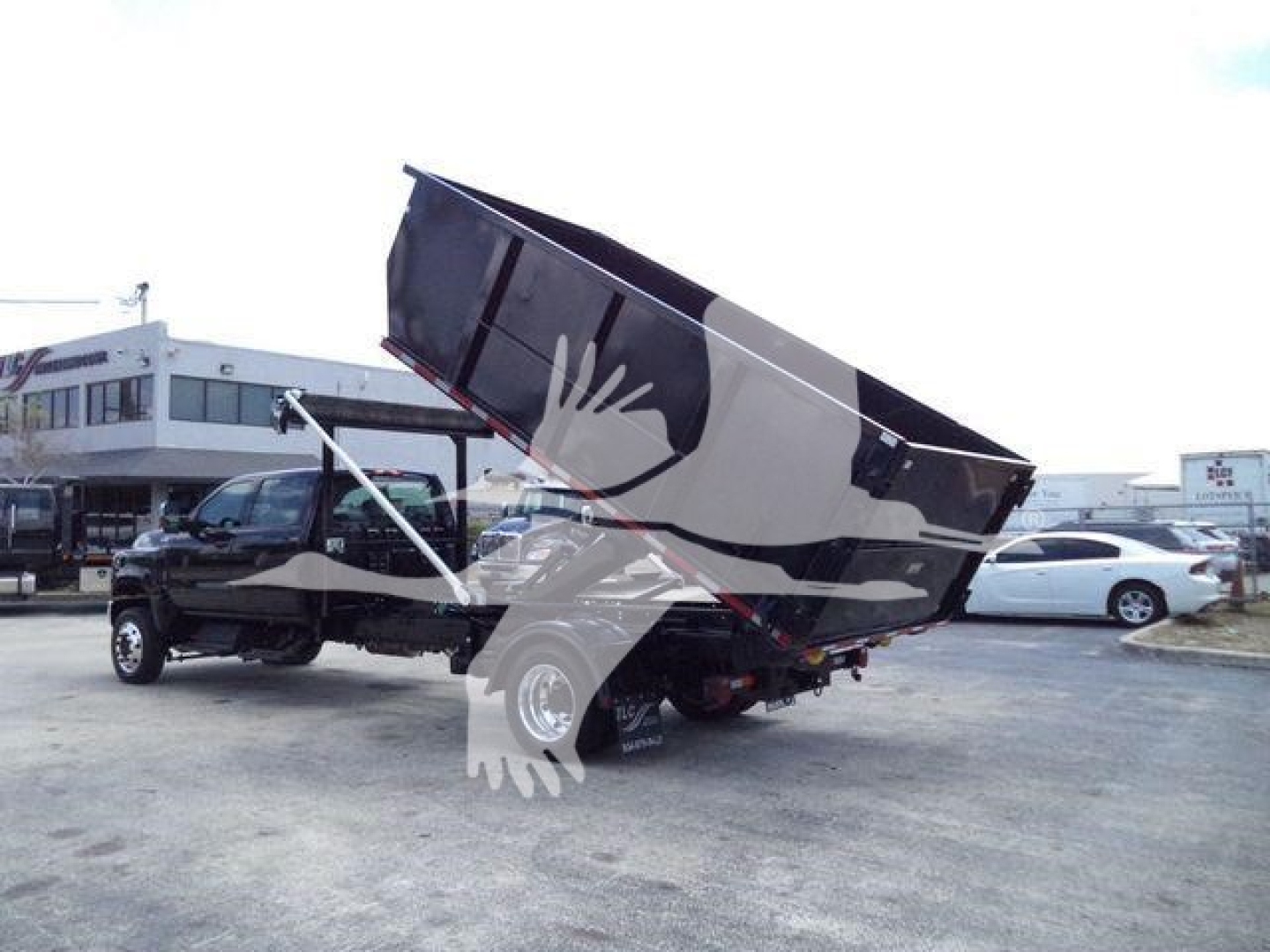 New International CV roll-off truck with bed raised showing hydraulic system and cab at a dealership lot.