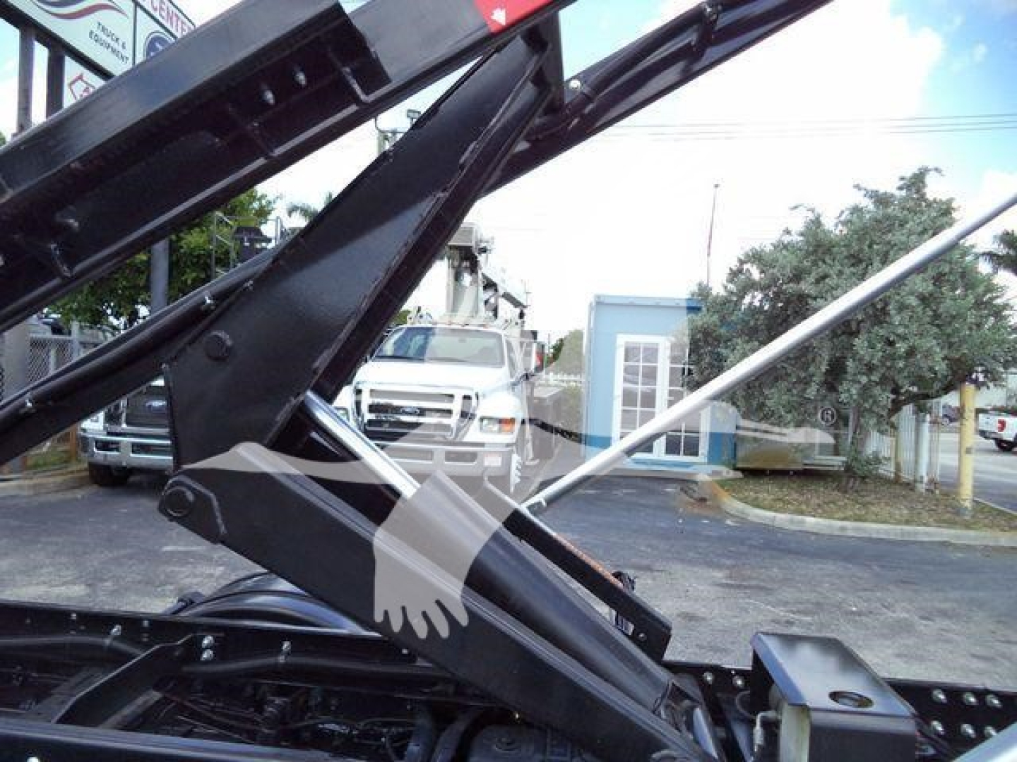 Equipment image showing a 2023 International CV roll-off truck component with hydraulic arms and black metal frame, no visible text