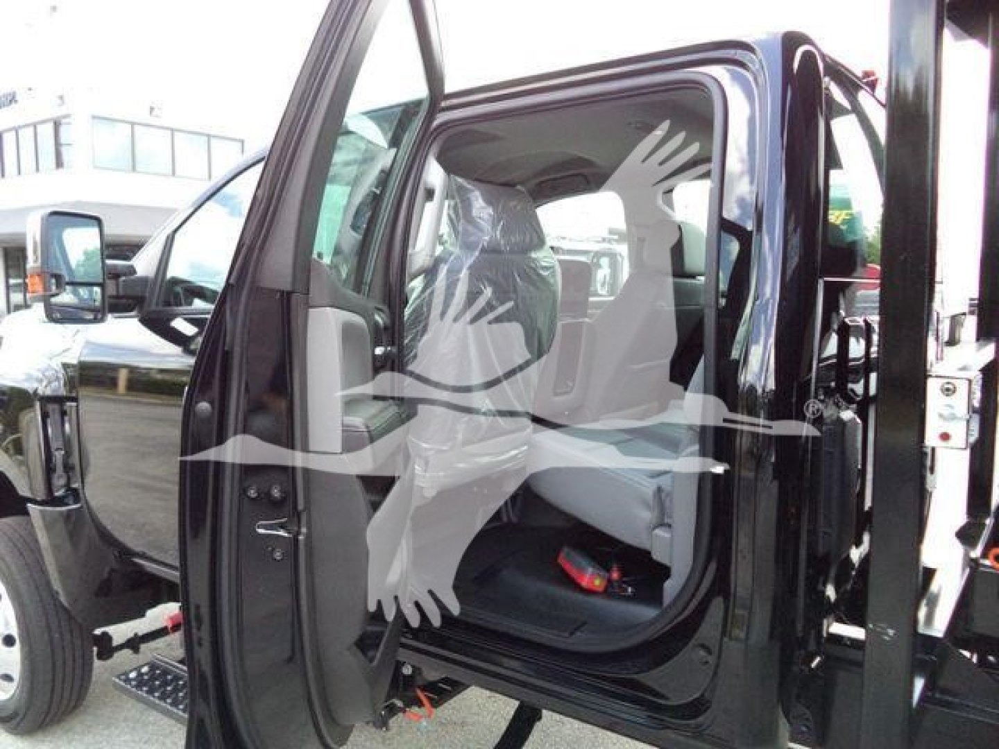 Truck cab interior visible through open driver door of a 2023 International CV roll-off truck; front bench seat, step, and side mirror visible.