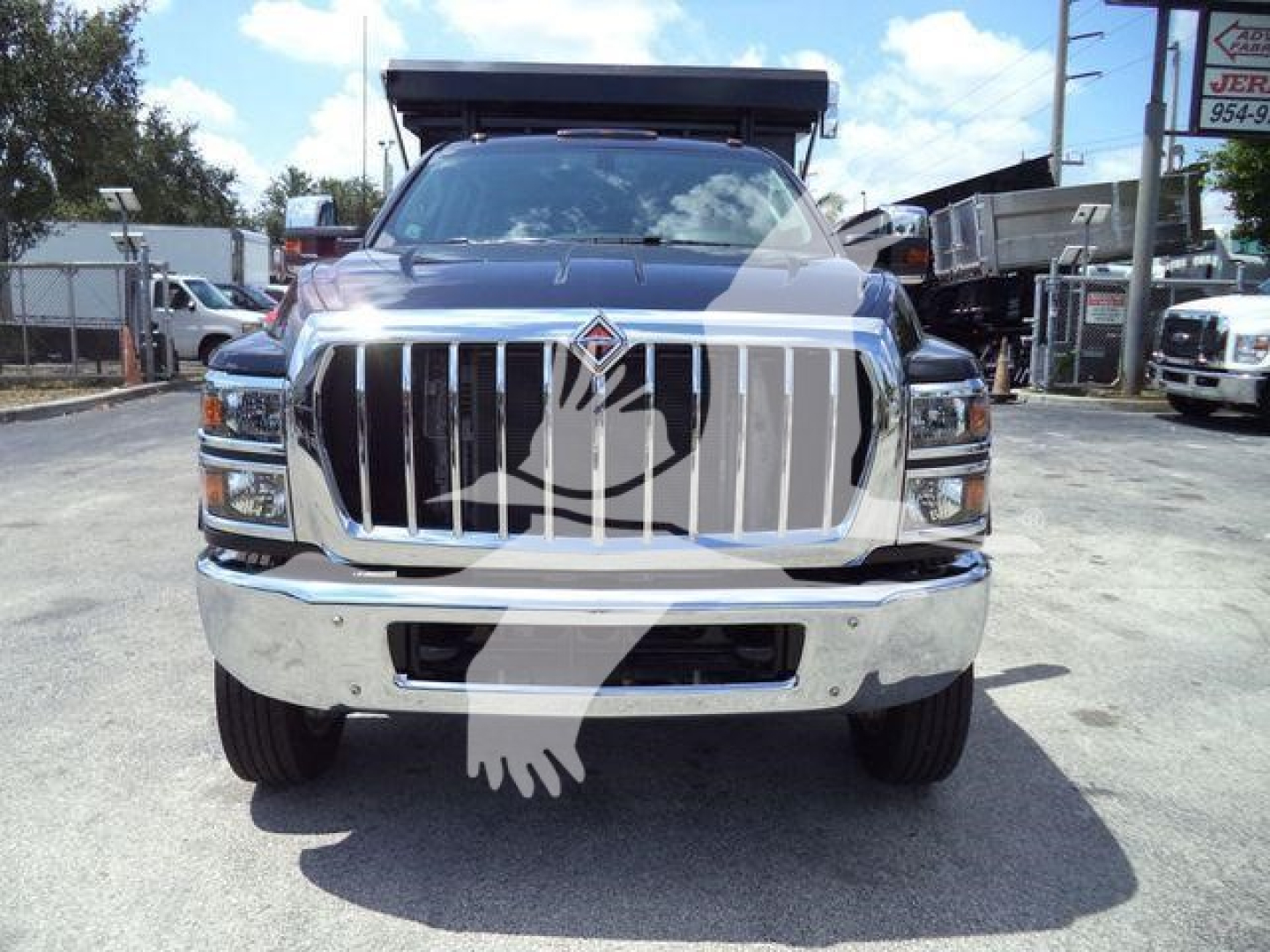 Front view of a 2023 International CV roll-off truck showing large chrome grille and emblem, with headlights and bumper visible.