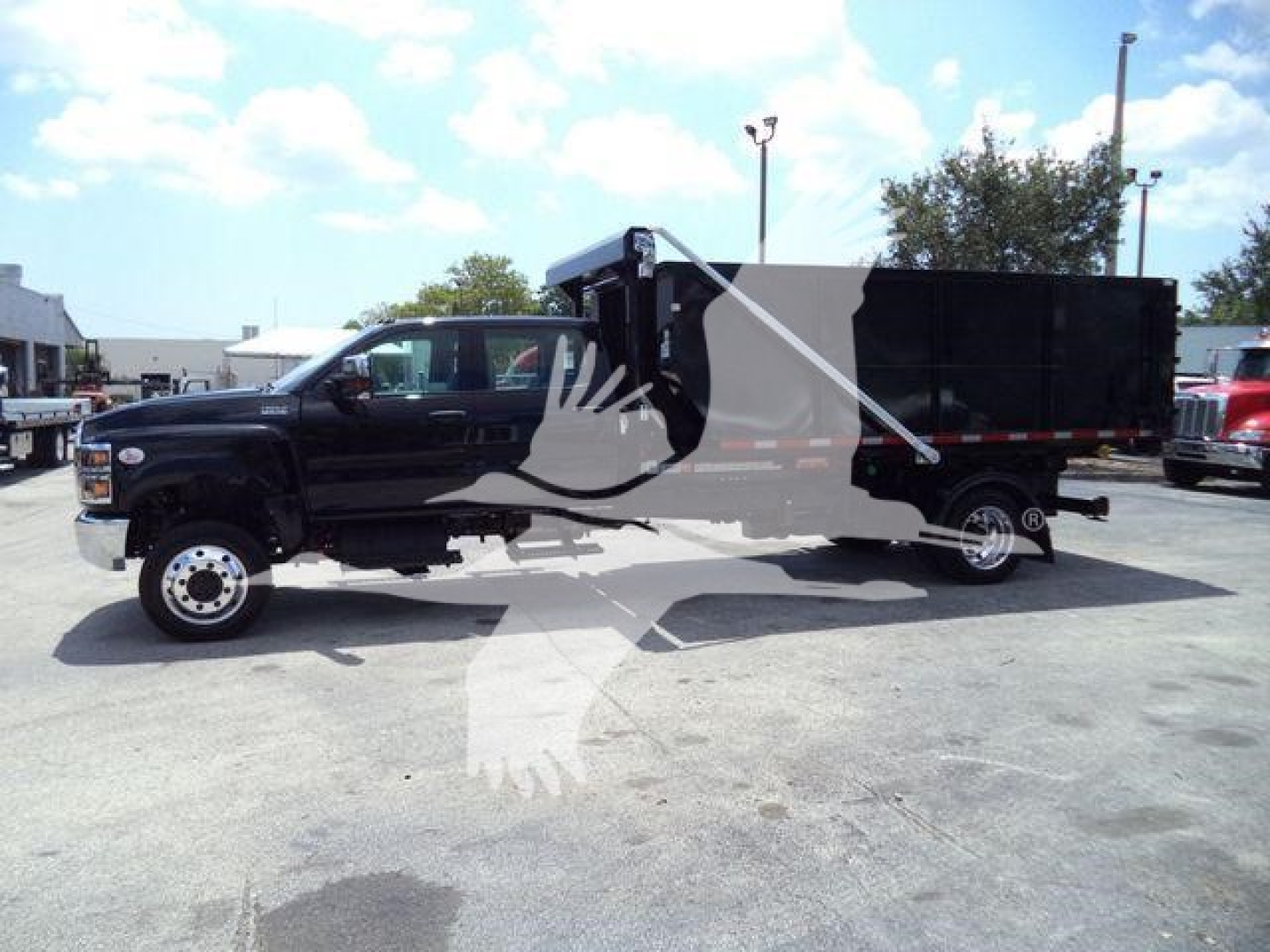 Truck cab and dump body in a dealership lot; black International CV-series roll-off truck with long dump body and dual rear wheels