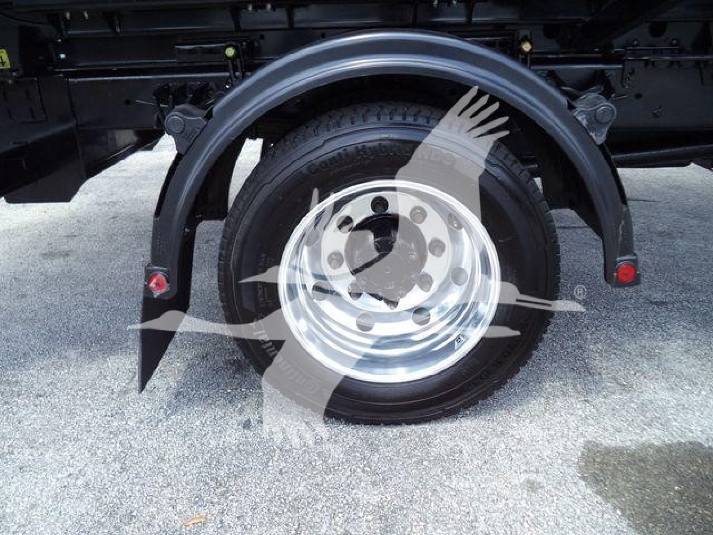 Wheel assembly and fender of a new International CV roll-off truck showing front wheel with chrome rim and black tire