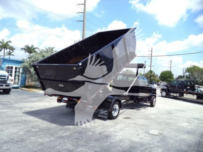 Dump trailer showing black CV515 rollover dump bed with dual wheels and hitch, in-service, in a dealership lot.