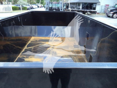 Image of a black truck bed in a new 2023 International CV roll-off, showing empty cargo space with glossy sides and floor; no visible text inside.