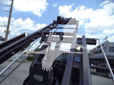 Truck-mounted crane arm and cab of a 2023 International CV rolloff truck showing hydraulic boom and operator area.