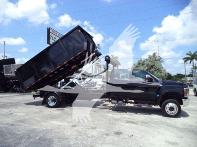 Truck with raised dump bed on a black International CV chassis, side view showing hydraulic lifting mechanism and dual rear wheels.