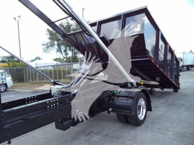 Truck bed on a new International Cv roll-off chassis showing hydraulic arms and a raised dumping container.
