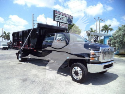 Box truck chassis with black dump body on a heavy-duty International CV series cab; front chrome grille, dual rear axles, and side steps, in a dealership lot.