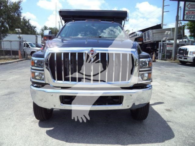 Front view of a 2023 International CV roll-off truck showing large chrome grille and emblem, with headlights and bumper visible.