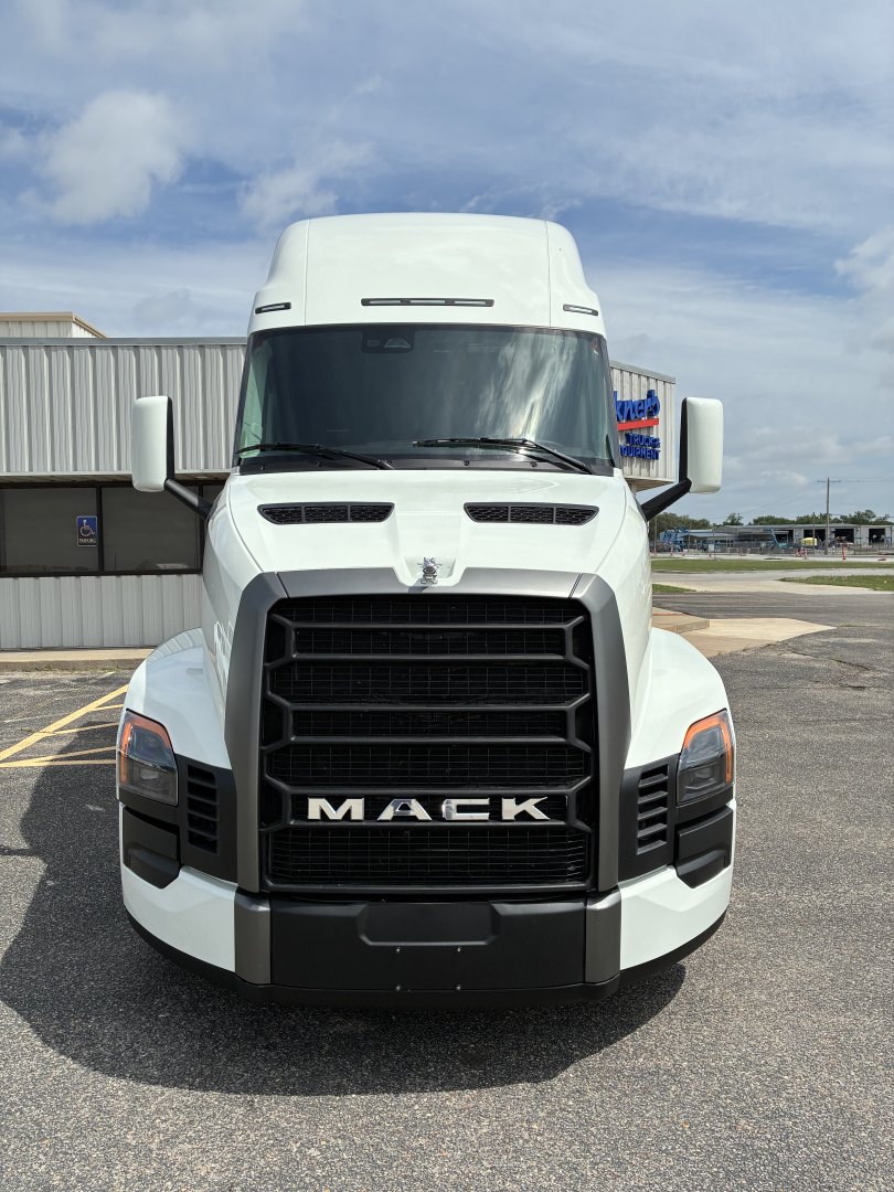 Front view of a white 2027 Mack PR64T76H truck with large black grille, Mack logo on hood, side mirrors, and bumper.