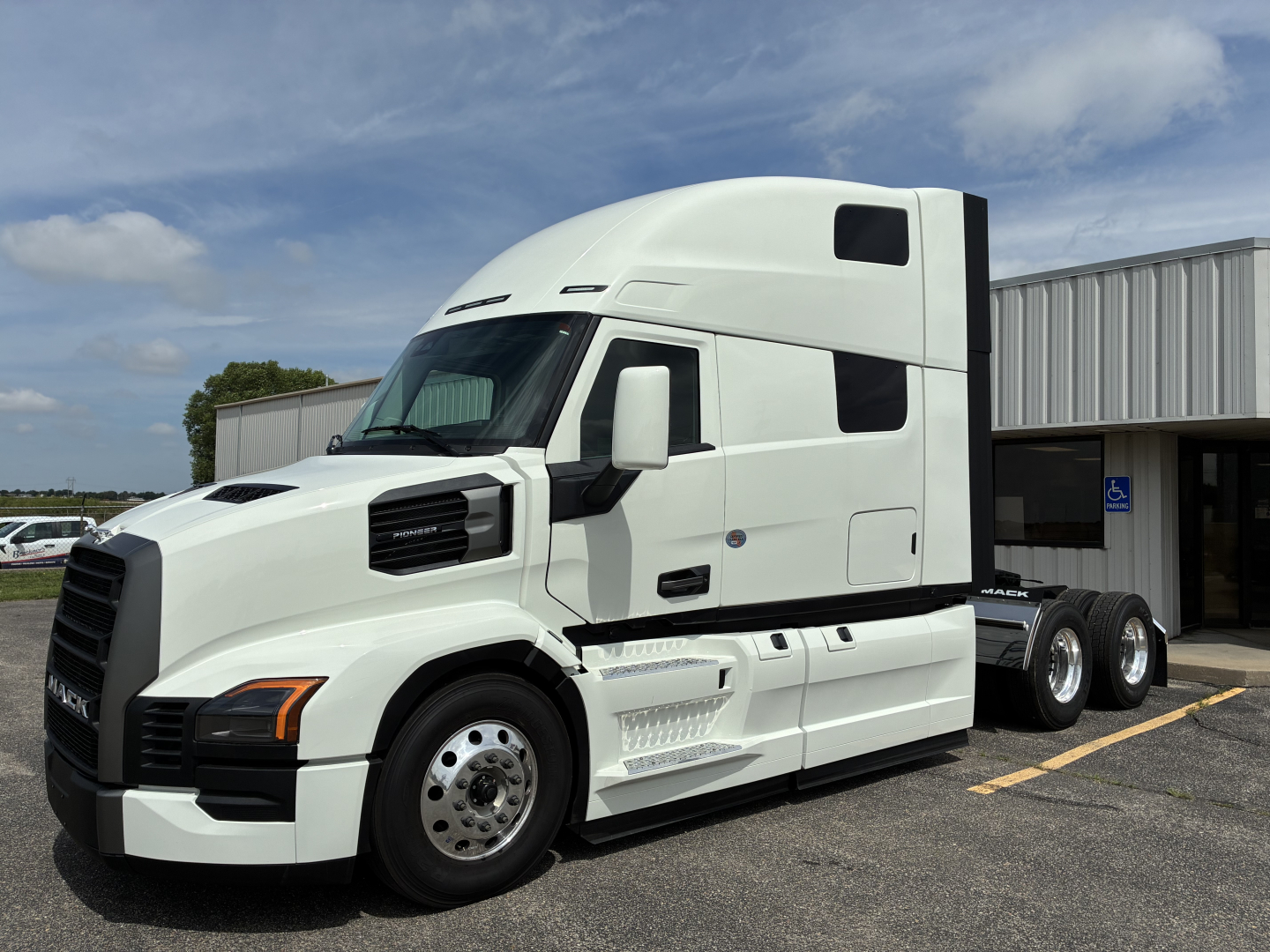 Tractor truck side view showing front cab and chassis with white exterior and aerodynamic design, Mack PR64T76H model text not visible.