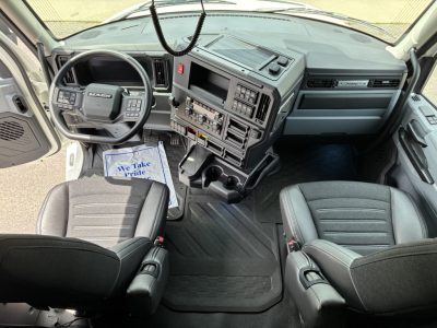 Mack PR64T76H truck cab interior showing steering wheel, dashboard, and front seats.