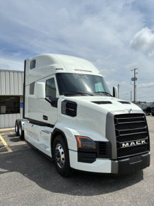 Mack PR64T76H conventional sleeper truck showing front grille with MACK branding and large side mirrors.