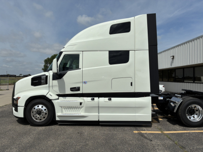 Truck side profile showing white Mack PR64T76H sleeper cab with aerodynamic design and black side panel.