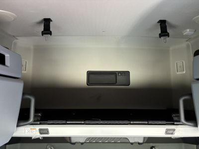 Cab interior storage area of a Mack PR64T76H sleeper cab with overhead hooks and a central storage compartment.