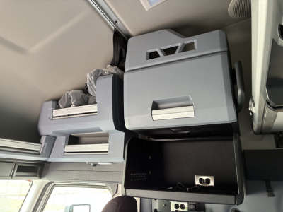 Cab interior showing storage compartments and a small open console drawer with a metal latch.