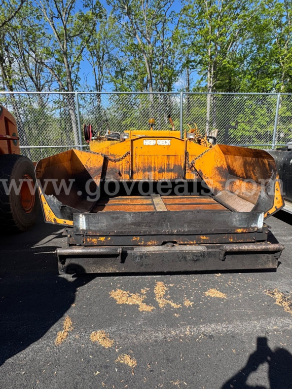 Mack unmarked asphalt hot oil truck bed attachment showing orange body and front cutting edge.