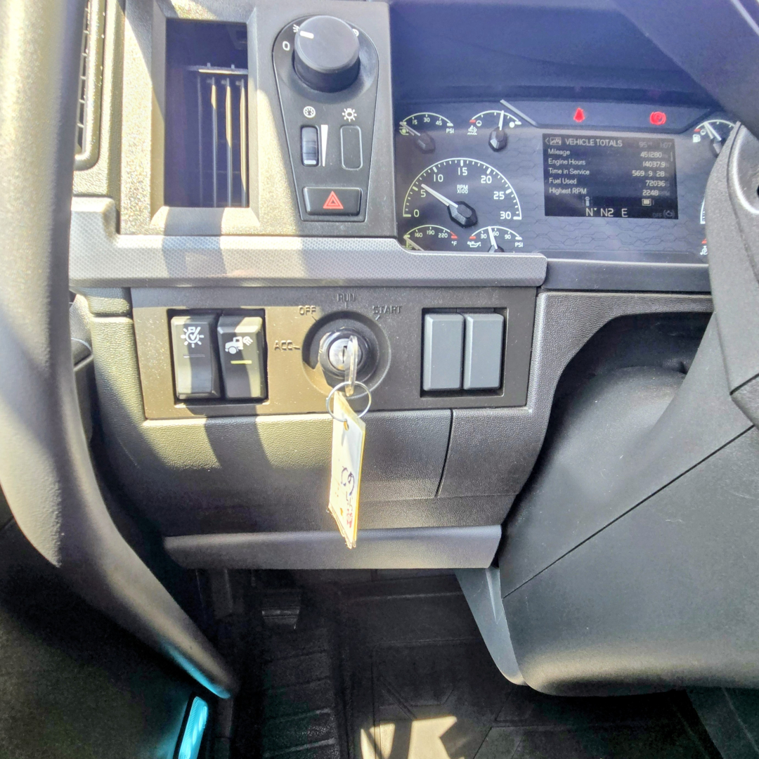 Volvo VNL truck dashboard and ignition area with key in ignition, steering column, instrument panel, and control switches visible.
