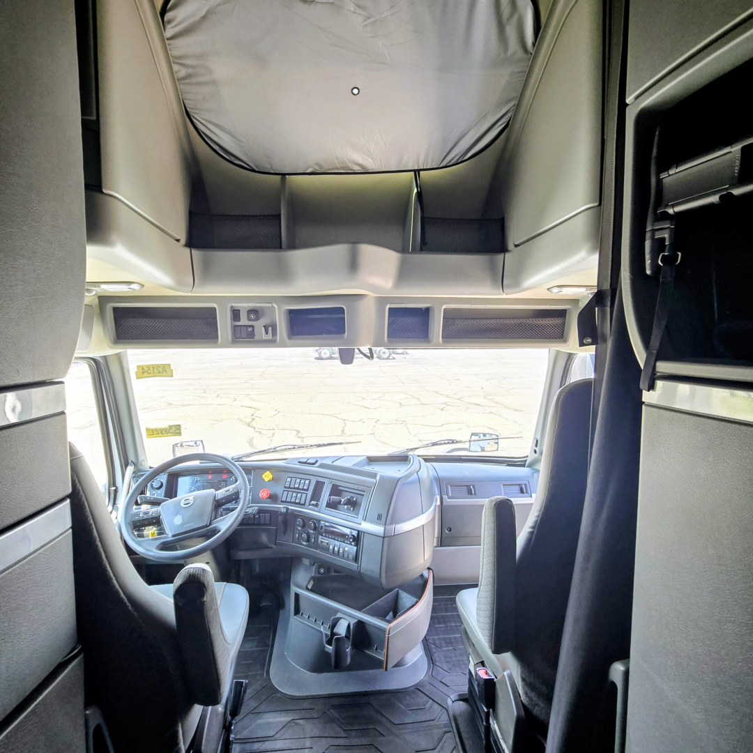 Cab interior of a 2022 Volvo VNL64T860 truck showing the driver seat, dashboard, steering wheel, overhead bunk area, and windshield; no legible labels or stickers visible.