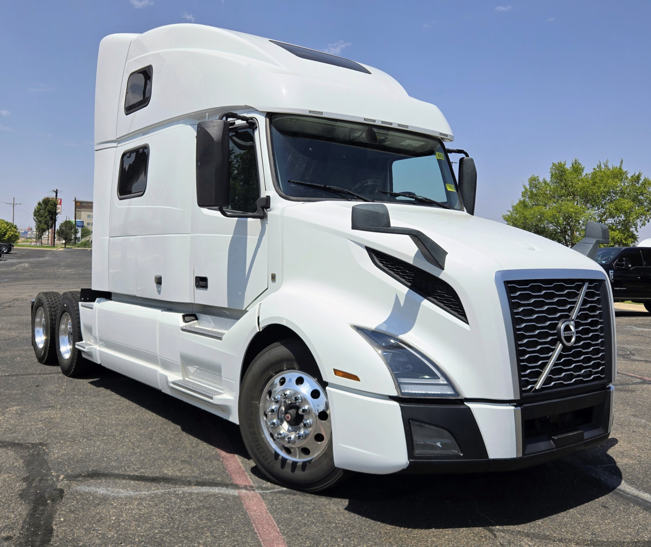 Volvo VNL64T860 tractor truck in white, side view showing front grille, cab and sleeper with chrome wheels.