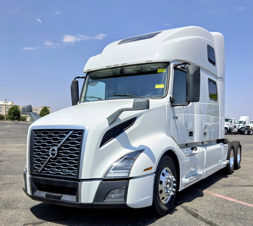 Volvo VNL64T860 semi-truck tractor in white, front-left view, showing grille, headlights, side mirrors, and sleeper cab.