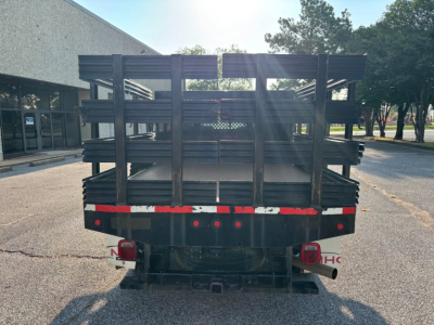 Ford F-250 stake bed shown from rear view with metal stake sides and tail lights.