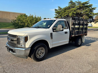 Ford F-250 stake bed truck shown in side view with white cab and black stake bed panels.