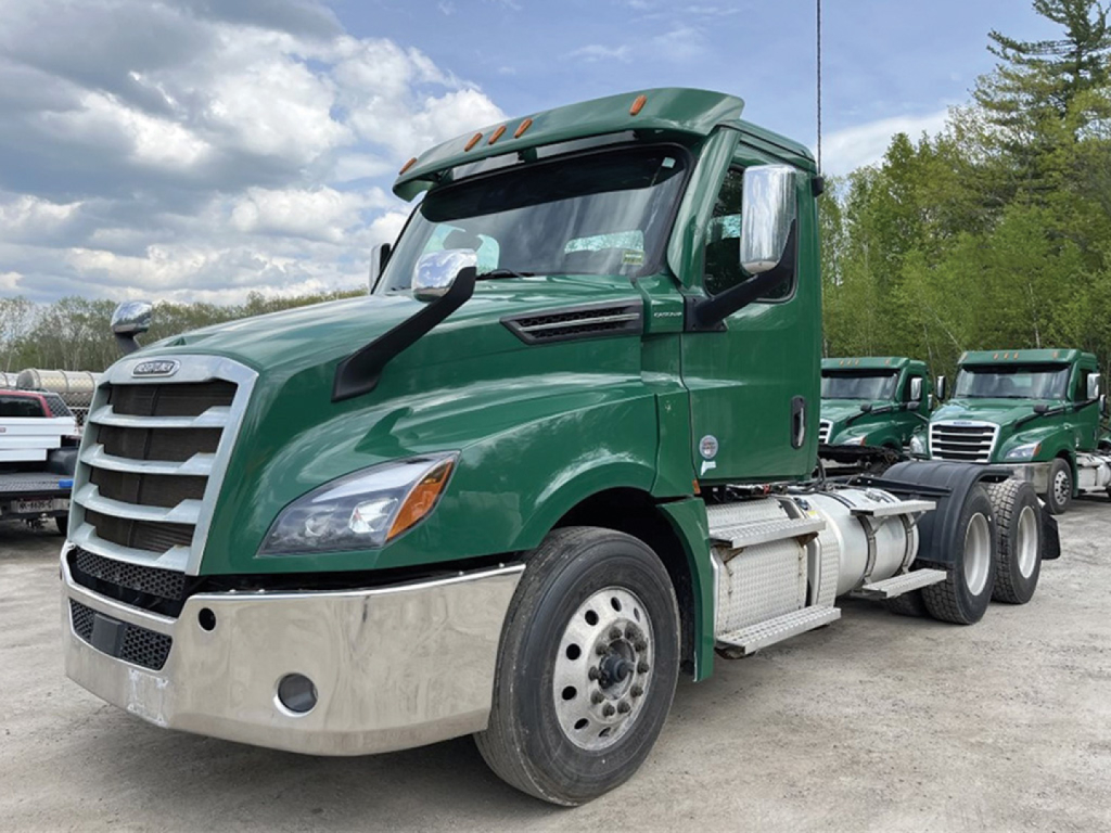 Freightliner Cascadia 126 cab chassis in green with chrome bumper and tandem rear wheels, front view.