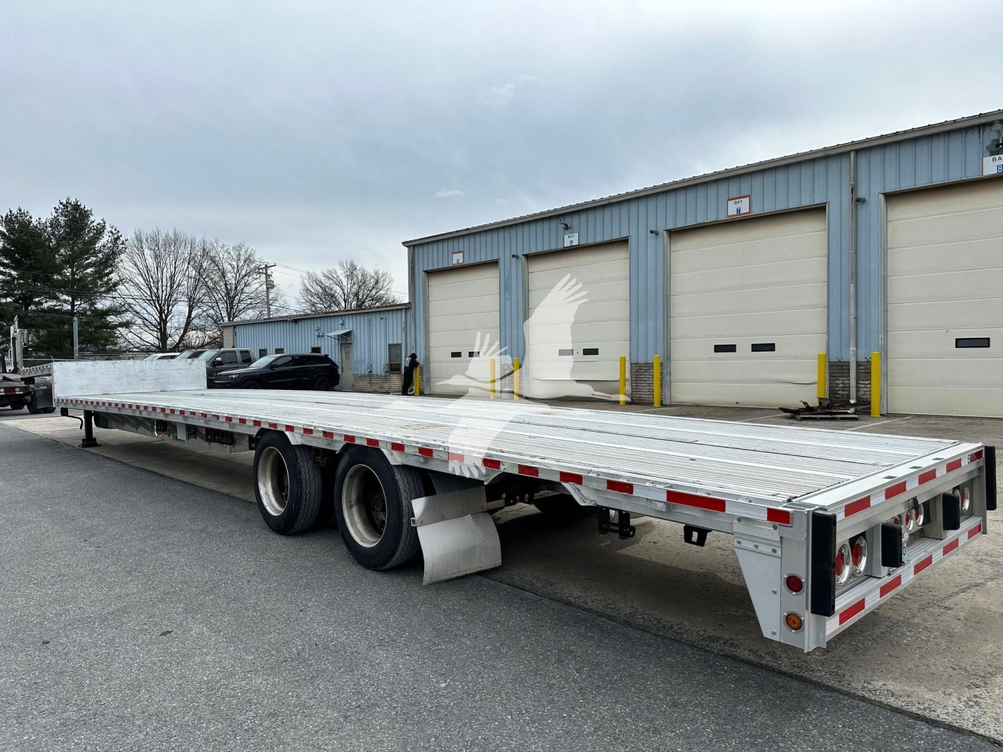 2019 Reitnouer Dropmiser trailer showing long aluminum drop deck with dual rear wheels, rear lighting, and signage on side.