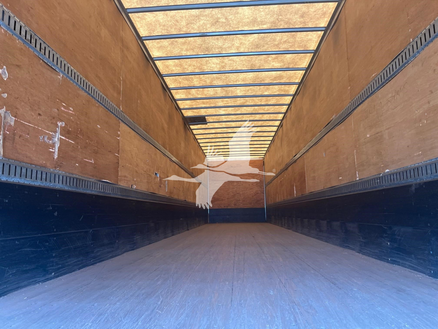 Trailer interior showing wooden side walls, metal rails, and upper ribbed ceiling in a Great Dane sheet and post roll door trailer.