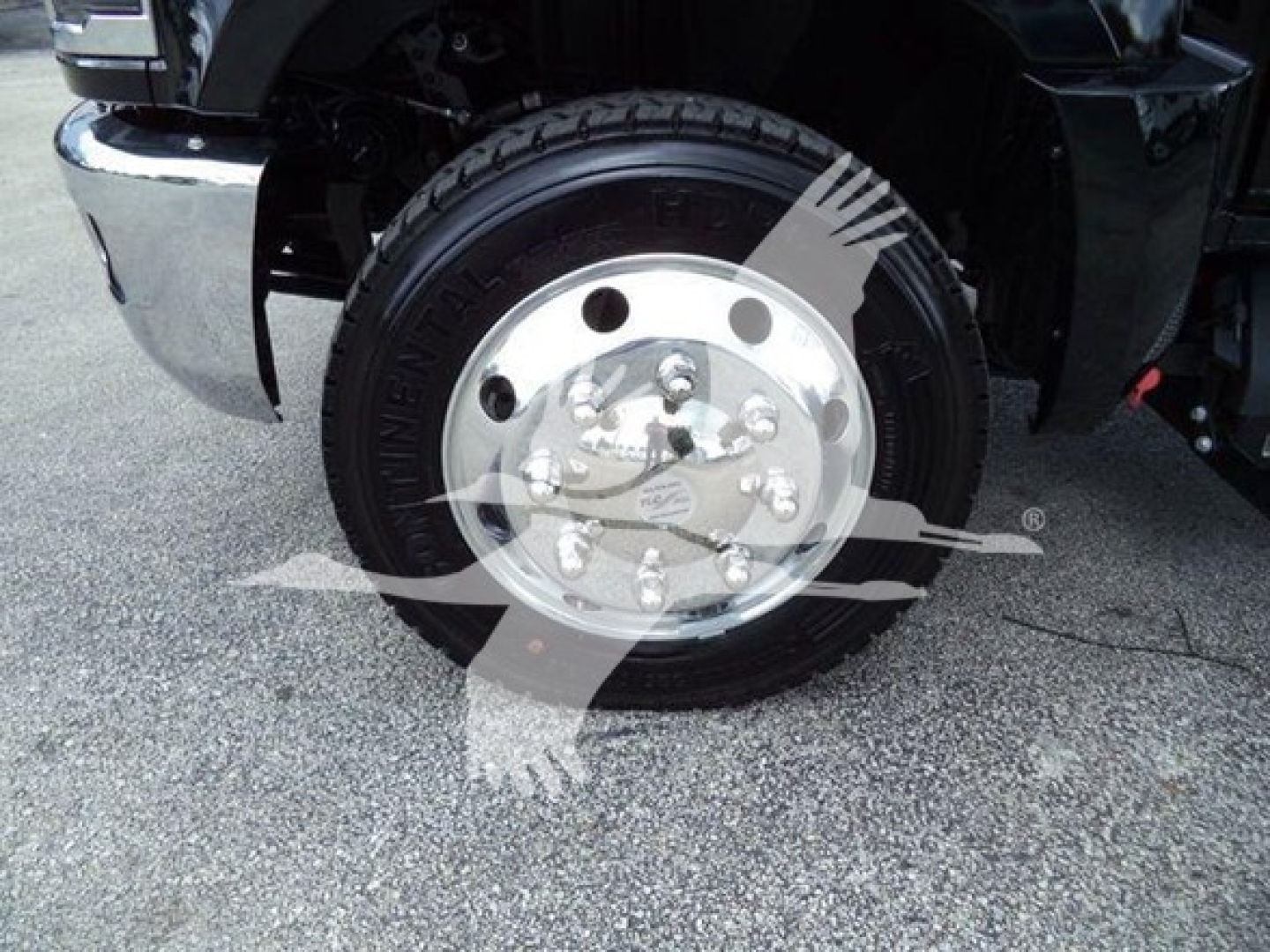 Front wheel and tire of a 2023 Chevrolet Silverado 6500HD rollback truck showing steel wheel and tire details.