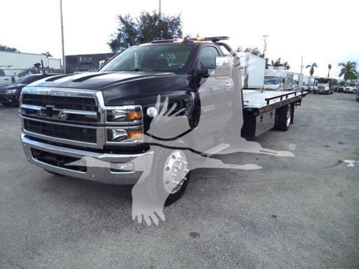 Chevrolet Silverado 6500HD rollback truck in a dealership lot with a long flatbed and front grille visible.