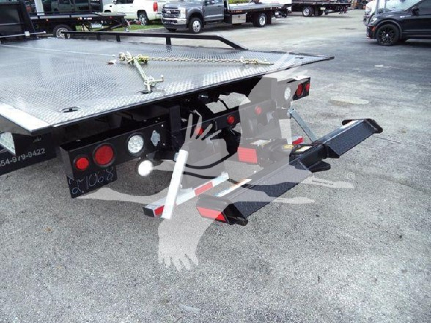Rear view of a 2023 Chevrolet Silverado 6500HD rollback truck showing tow hitch, hydraulic controls, and heavy-duty flatbed with diamond plate surface.