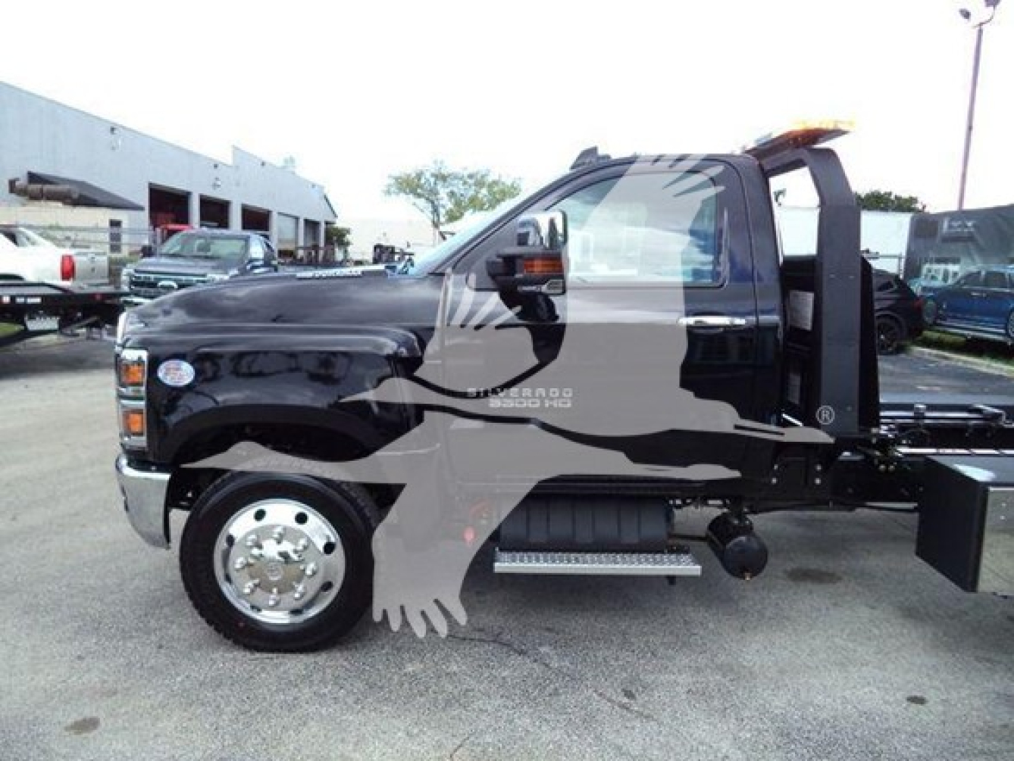Truck cab side view showing Chevrolet Silverado 6500HD chassis with single rear wheel and equipment for rollback service.