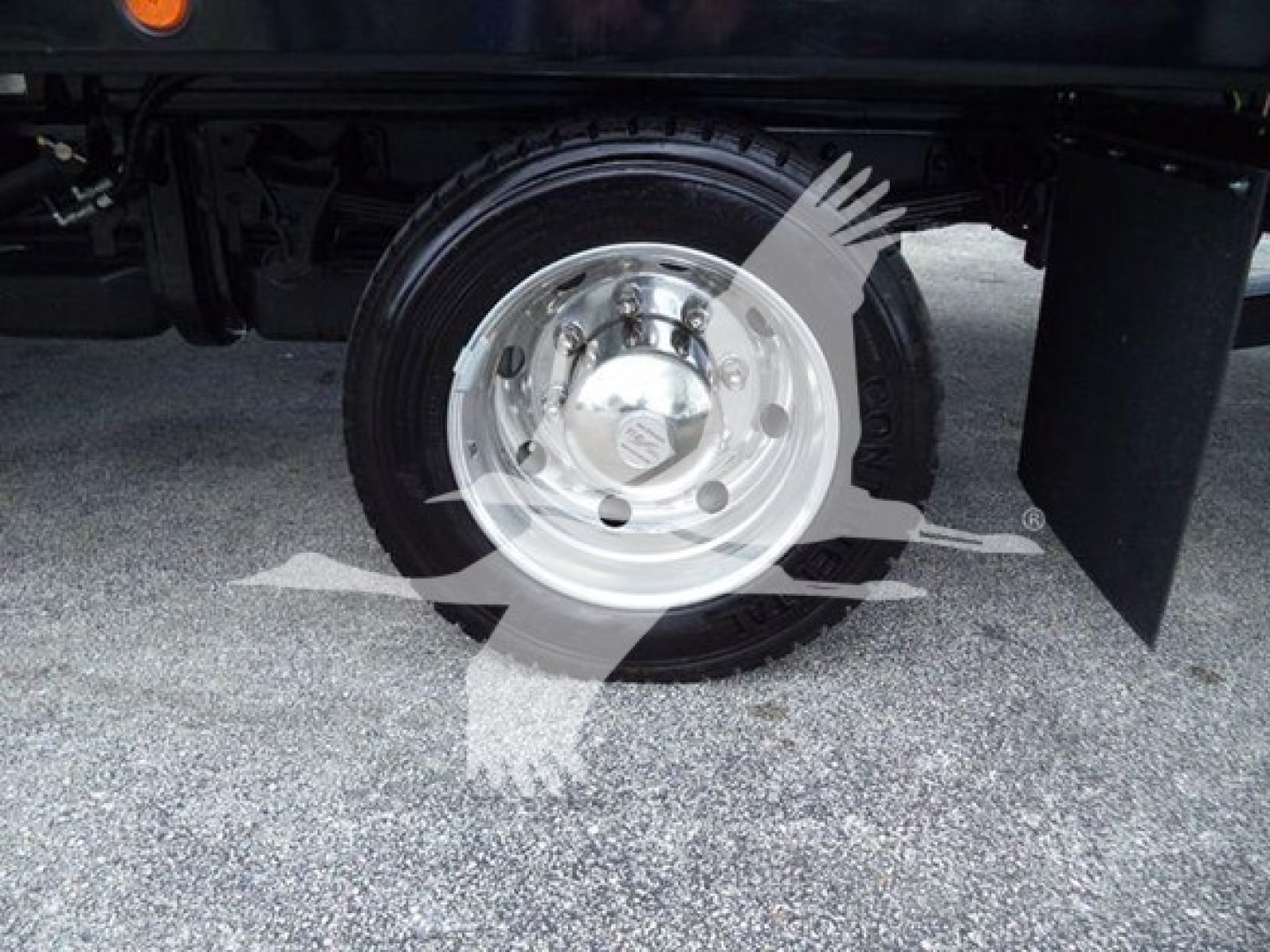Wheel and hub of a 2023 Chevrolet Silverado 6500HD rollback truck showing polished steel hubcap and black tire.