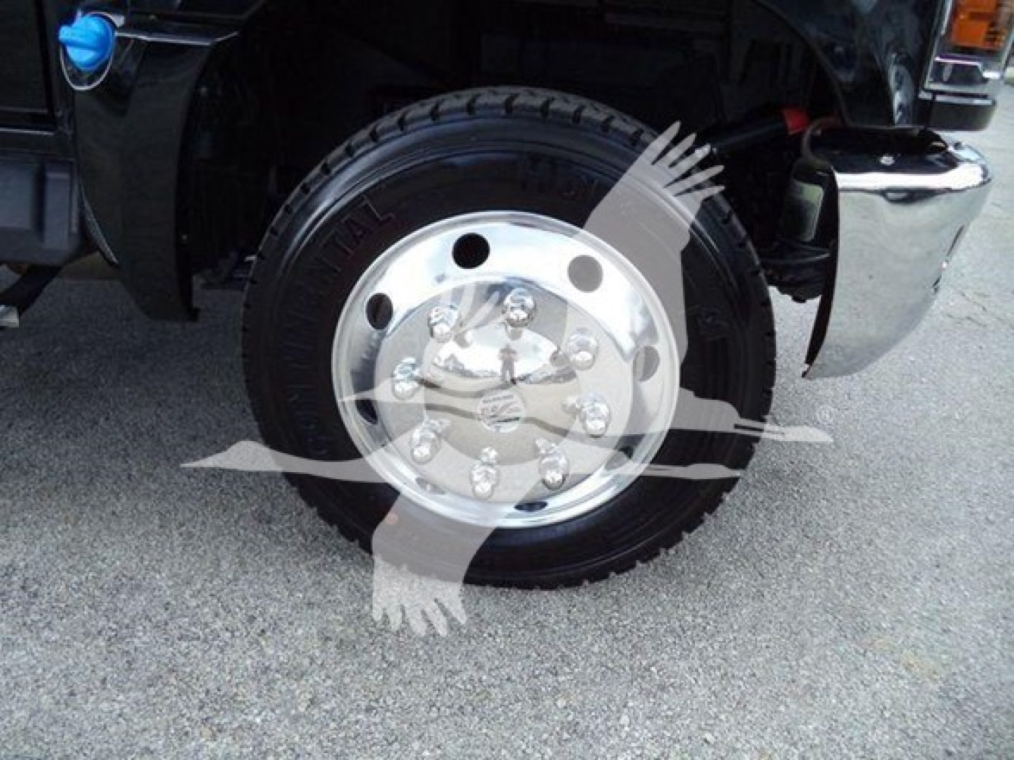 Truck wheel and chrome hubcap close-up on a Chevrolet Silverado 6500Hd rollback truck showing front wheel with black tire and chrome lug nuts.