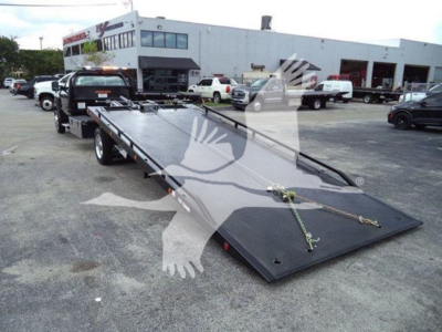 Tow truck flatbed tow rig in a dealership lot with white and black equipment, Silverado 6500Hd listing text overlaid.