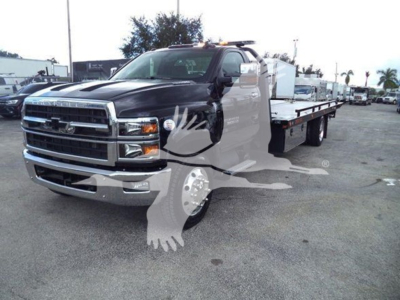 Chevrolet Silverado 6500HD rollback truck in a dealership lot with a long flatbed and front grille visible.